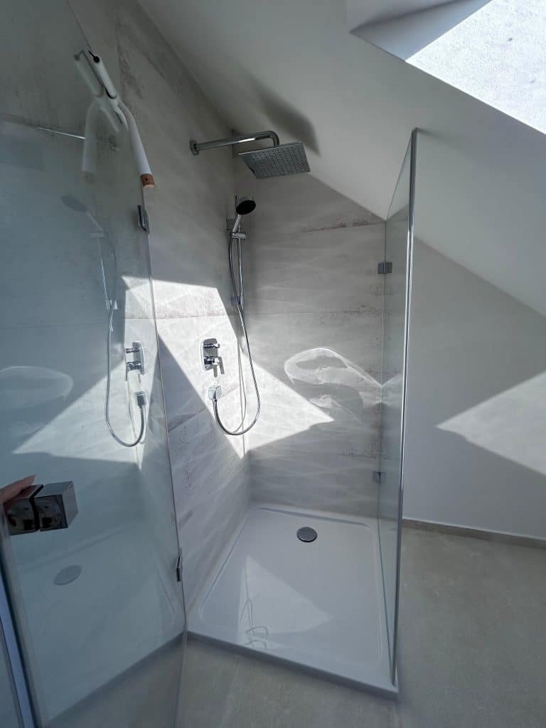 Helle Dusche mit Glaswand und Regendusche nach Badsanierung in Augsburg